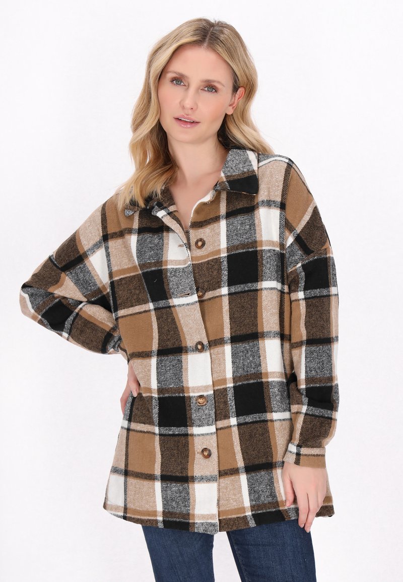 Brun, svart och vit rutig flanellskjorta med krage och knapplåsning. Löst sittande med långa ärmar och strukturerat tyg.