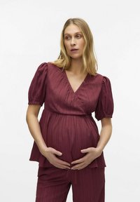 Completo per maternità composto da top e pantaloni in bordeaux, con maniche corte a sbuffo e scollatura a V. Tessuto testurizzato con pieghe sottili per una dimensione aggiuntiva.