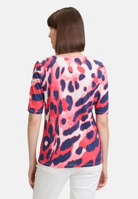 Short-sleeve t-shirt featuring a bold red, pink, and navy leopard print design. Made of soft fabric with a relaxed fit and round neckline.