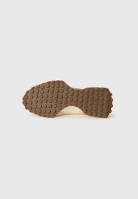 Talpă de pantof cu un profil din cauciuc maro, având modele circulare de prindere pe un fundal deschis.