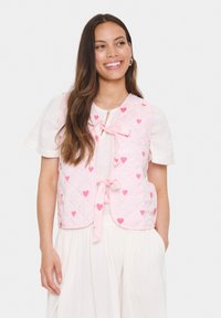 Svetlo roza prešita brezrokavnik z razpršenimi majhnimi rdečimi srci, z zavihkom za zapiranje spredaj in okroglim izrezom.