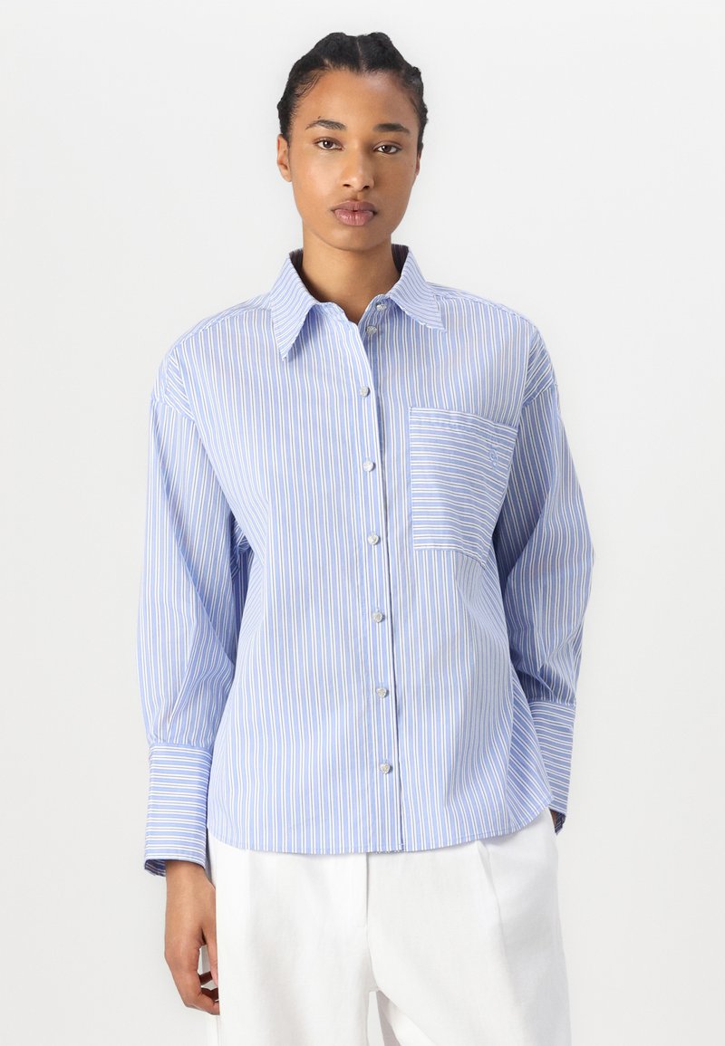 Niebieska i biała koszula w paski z zapięciem na guziki, kieszenią na piersi i długimi rękawami. Posiada klasyczny kołnierzyk i gładką teksturę materiału.