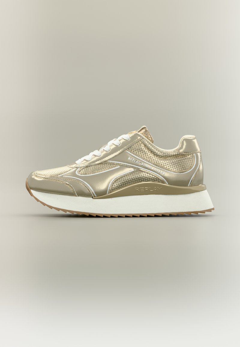 Αθλητικό παπούτσι σε χρυσό τόνο με εξωτερικό από δίχτυ και γυαλιστερό υλικό, διαθέτοντας λευκή ελαστική σόλα, στρογγυλή μύτη και έντονο σχέδιο κορδονιών με λεπτομέρειες επωνυμίας.