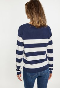 Marineblauw en witte gestreepte trui, met een ronde hals en lange mouwen, gemaakt van een zacht gebreid materiaal. Geribbelde zoom en manchetten.