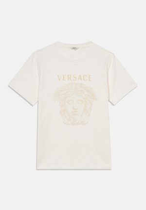 T-shirt blanc à manches courtes avec un graphisme beige représentant une tête de Méduse et le mot « VERSACE » imprimé au-dessus du motif sur le devant.