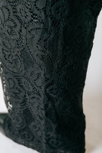 Fekete csipke anyag virágmintákkal és bonyolult részletezéssel, sima textúrával és egy varrással az oldalon.