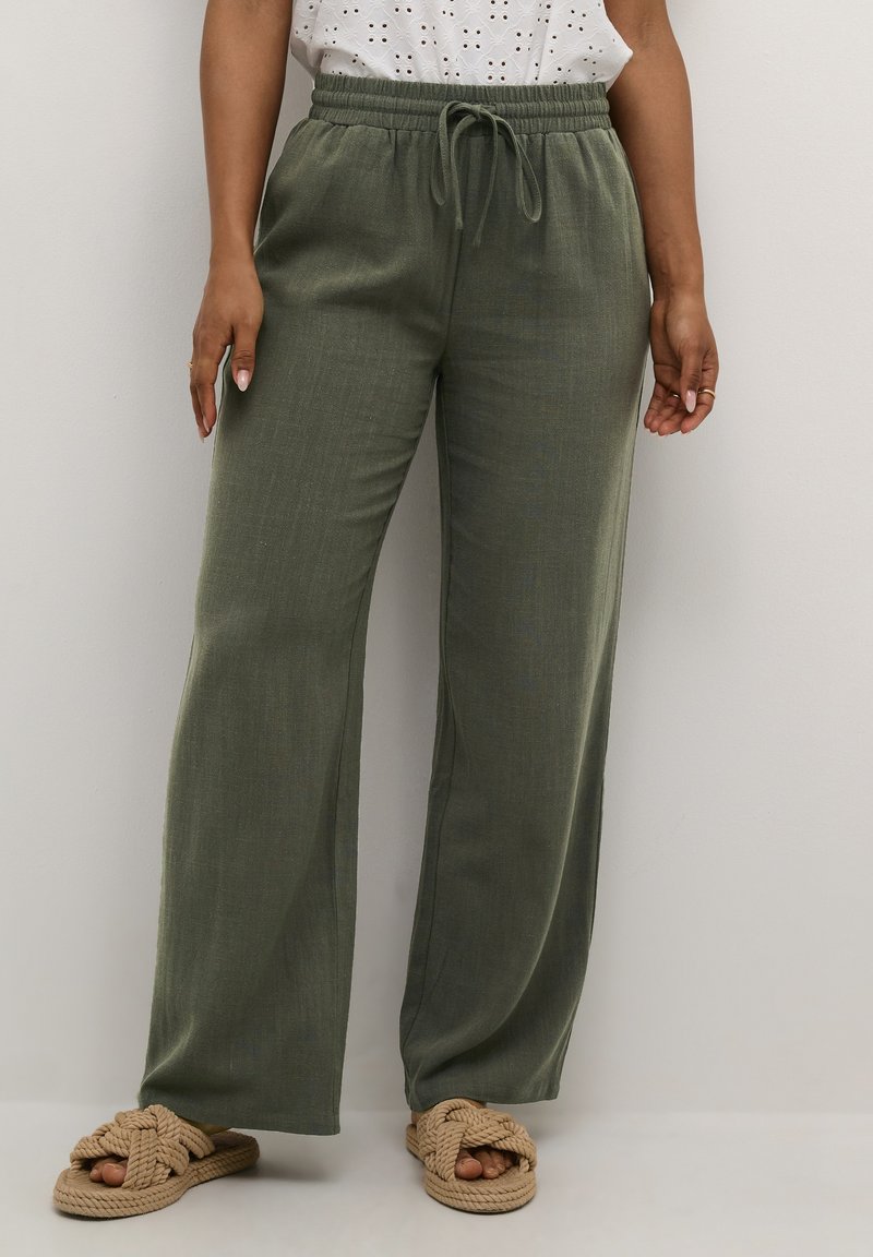 Olive green wide-leg pants with an elastic waistband and drawstring. Made of lightweight fabric, featuring a smooth texture. Paired with tan sandals.