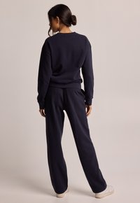 Completo di felpa e pantaloni larghi in blu navy. Tessuto morbido con polsini e vita a coste.