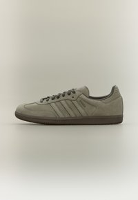 Gray suede sneaker with three tonal stripes, rounded toe, lace-up closure, and textured rubber sole. Minimalist design.
