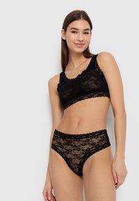 Bralette en dentelle noire et culottes taille haute assorties. Comprend des motifs floraux, des bords festonnés et une texture translucide.