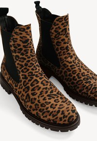 Leopard print suede Chelsea boots featuring black elastic side panels and a textured rubber sole for grip.