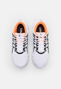 Scarpe sportive bianche con una tomaia in rete testurizzata, caratterizzate da dettagli neri e arancioni sul colletto e sulla linguetta. Lacci neri.