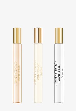 Tre flaconi sottili di profumo Jimmy Choo I Want Choo con tappi dorati, ciascuno contenente diverse tonalità di liquido.