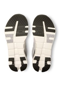 Le suole delle scarpe da corsa presentano un battistrada in gomma nera testurizzata con accenti bianchi e grigi e un design segmentato per garantire aderenza e flessibilità.