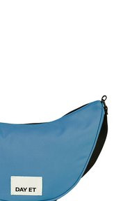 Borsa in nylon blu con design curvo, zip nera e tracolla regolabile. Presenta un'etichetta bianca con il testo "DAY ET" sul davanti.