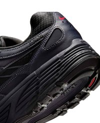 Chaussure de course Nike noire avec semelle texturée, logo swoosh rouge au talon et "L-6700" embossé près du col de la cheville.