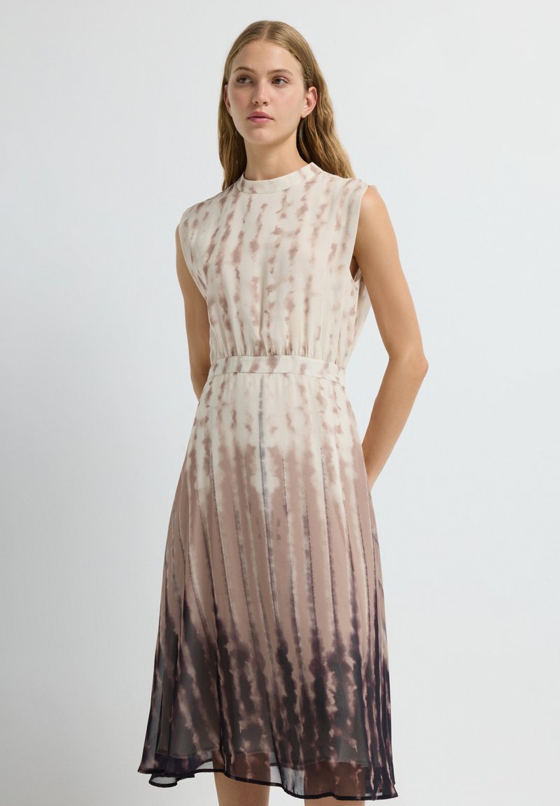 Vestido sin mangas en un degradado de beige claro a oscuro, con un diseño plisado y un efecto ombre que transiciona a marrón oscuro en el dobladillo.