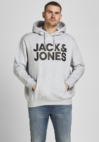 Grijze hoodie met een kangoeroezak, voorzien van "JACK & JONES" in dikke zwarte letters. Gemaakt van katoenmix, ontspannen pasvorm en ribgebreide cuffs.
