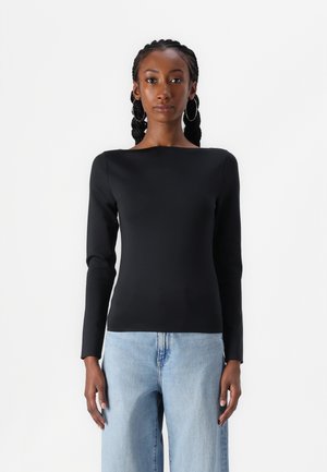 Top nero a maniche lunghe con scollatura a barco, texture liscia, vestibilità slim, abbinato a jeans a gamba larga di colore blu chiaro. Design semplice e moderno.