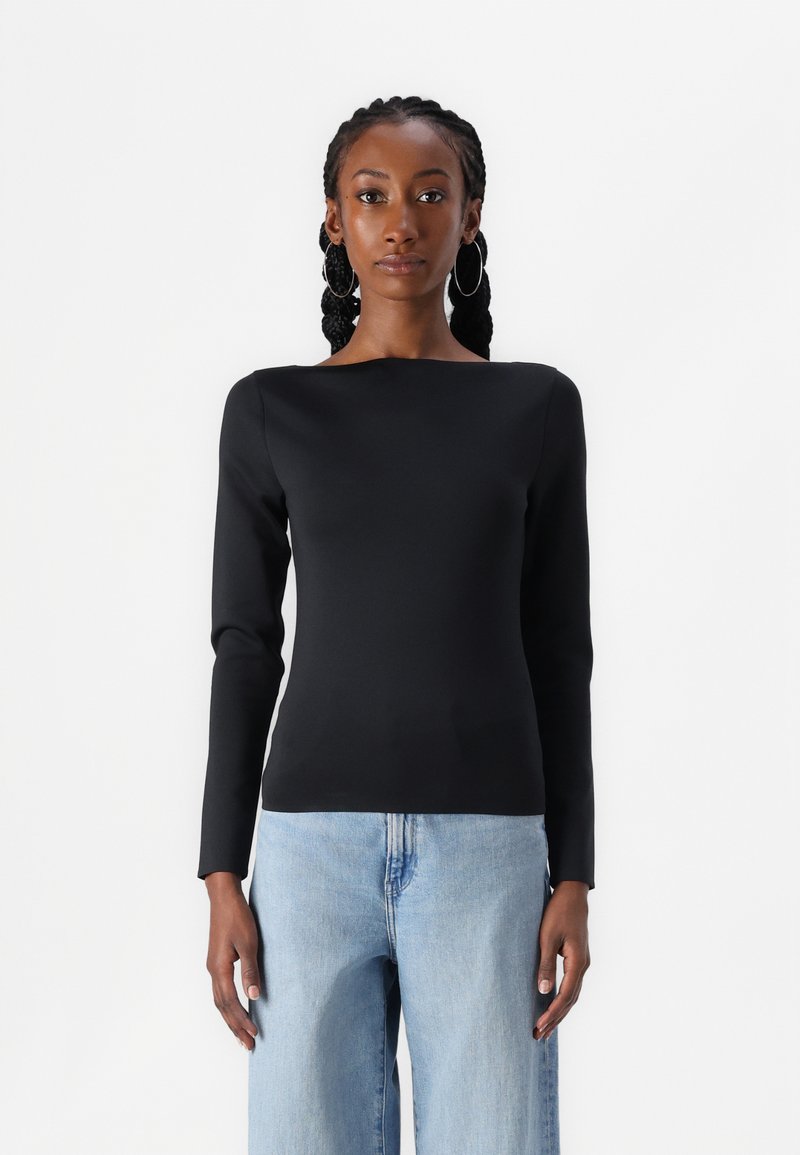 Black long-sleeve top with a boat neckline, smooth texture, slim fit, paired with light blue wide-leg jeans. Simple, modern design.