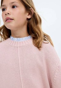 Ljust rosa stickad tröja med rund hals och ribbade detaljer. Under finns en blå och vit randig volangkrage.