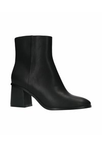 Bottes noires à la cheville en matériau synthétique lisse, avec un talon carré et une silhouette épurée. Aucun motif ou accent notable.