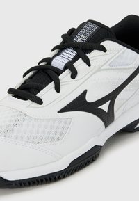 White athletic shoe featuring a mesh upper, black accents, textured surface, and a patterned tread on the sole for traction.