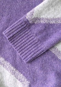 Maglione viola e grigio con polsini a coste, texture morbida e motivo diagonale sul tessuto. Finitura liscia con transizione di colore.