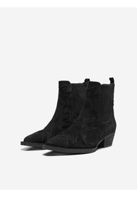 Bottines en suède noir avec un bout pointu, découpes incurvées sur les côtés, panneaux verticaux texturés et un petit talon empilé.