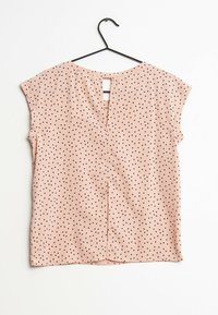Top rosa a maniche corte con pois neri, dotato di apertura a chiave nella parte posteriore e orlo dritto. Realizzato in un tessuto liscio e leggero.