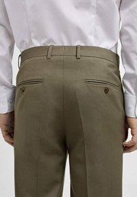 Olivgrüne, maßgeschneiderte Hose mit glatter Textur, ausgestattet mit zwei Gesäßtaschen mit Knopfverschluss und einem schlichten Bund.