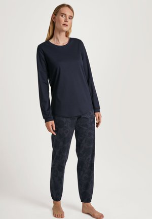 Marineblaues Longsleeve mit Rundhalsausschnitt, kombiniert mit marineblauen Jogginghosen mit Blumenmuster. Weicher Stoff, lockere Passform, elastische Bündchen an den Knöcheln.