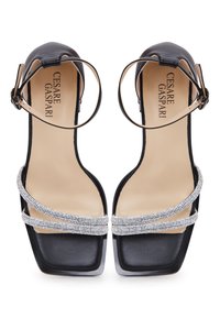 Zwarte hakken sandalen met een vierkante neus, voorzien van twee banden versierd met rhinestones en een dunne enkelriem. Glad bovenmateriaal.