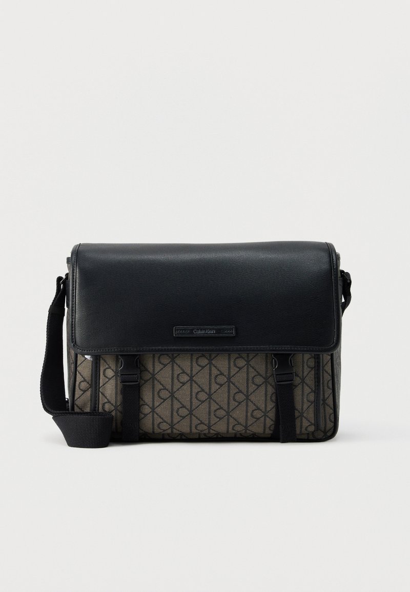 Μαύρη και καφέ επαγγελματική τσάντα Calvin Klein με ρυθμιζόμενο ιμάντα, κλείσιμο με καπάκι και επαναλαμβανόμενο μοτίβο με το λογότυπο "CK" στο ύφασμα του σώματος.