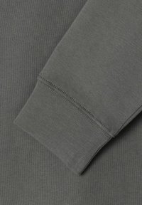 Manga de sudadera gris de algodón con puño acanalado, mostrando una textura suave y costuras uniformes a lo largo de las uniones.