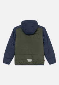 Olīvu zaļš un tumši zilas krāsas pufīgs jaka, kas aprīkota ar kapuci, quilted tekstūru un trim horizontālām atstarotājām joslām aizmugurē.