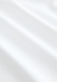 Tissu blanc avec des plis doux et des ombres subtiles créant une texture lisse et fluide.