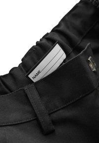Ceinture en tissu noir avec des fronces élastiques. Une étiquette d'entretien avec "NOM" et des lignes pointillées est visible. Accents en métal inclus.