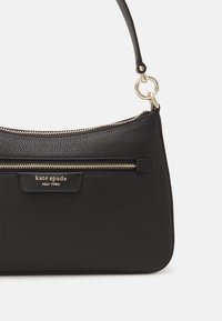 Black leather handbag with textured finish, gold hardware, and zipper details. Features a shoulder strap and logo accent.