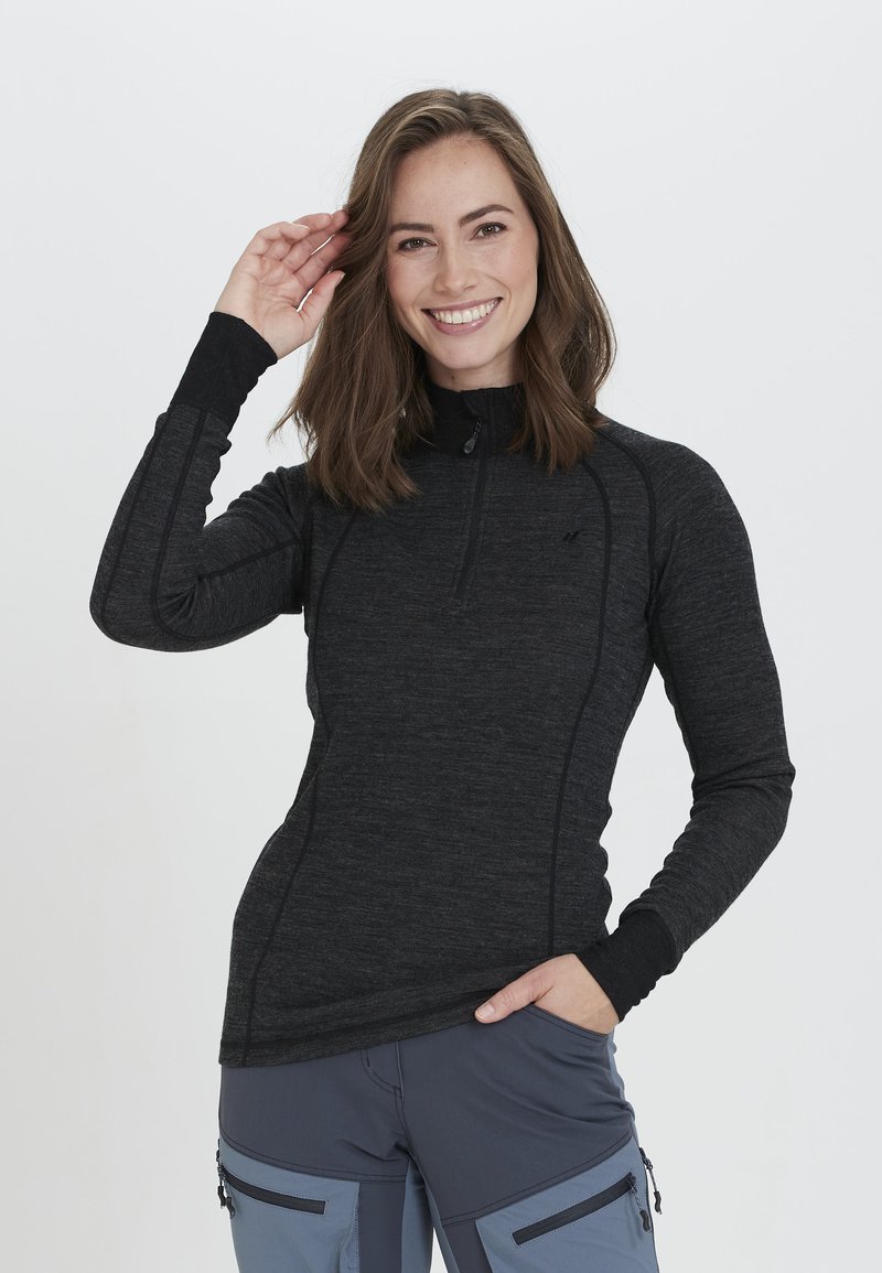 Musta pitkähihaine zip-up-toppi, jossa on korkea kaulus ja istuva muotoilu. Ominaisuuksiin kuuluu teksturoitu kangas ja hienovaraiset sauman yksityiskohdat. Malleilla on hymy kasvoillaan.