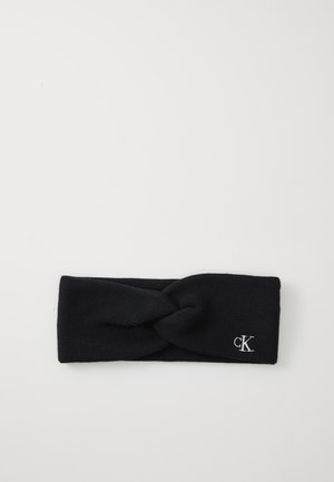 Dunkelblaue gestrickte Stirnband mit einem gedrehten Vorderdesign und gesticktem "ck"-Logo in Weiß an der Seite. Weicher Textur, breite Form.