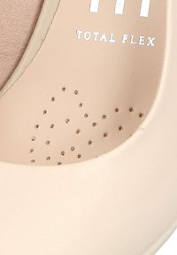 Zapato de cuero beige con punta redondeada y detalles perforados. Presenta "TOTAL FLEX" grabado en plata. Textura suave en toda su superficie.