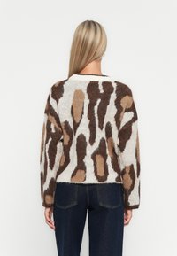 Brown and cream patterned sweater in soft, fuzzy material; loose fit with long sleeves and a rounded neckline.