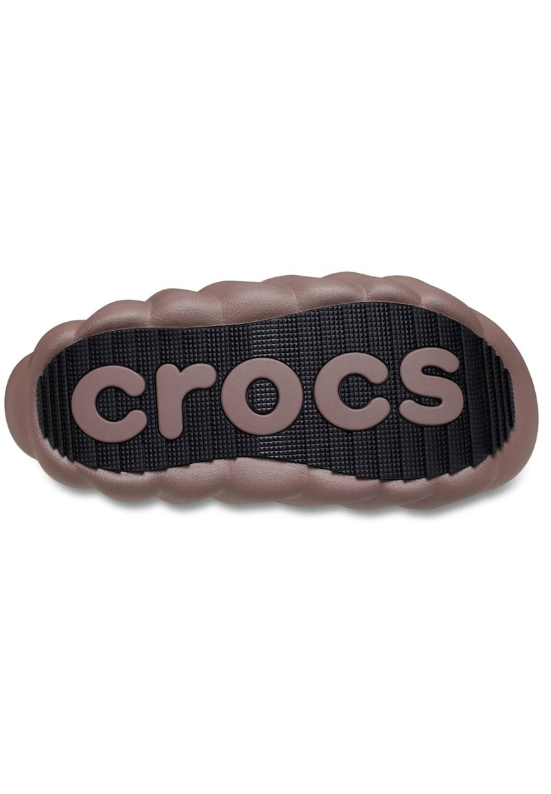 Brązowa gumowa podeszwa Crocs z teksturowanym czarnym bieżnikiem oraz wypukłym logo "crocs" w gładkim, jasnobrązowym wykończeniu. Zaokrąglone, wyściełane krawędzie.