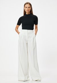 Top negro de canalé y pantalones anchos de tiro alto en blanco, con un diseño limpio, textura suave y bolsillos laterales.