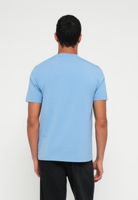 Ανοιχτό μπλε κοντομάνικο μπλουζάκι με στρογγυλή λαιμόκοψη, κατασκευασμένο από απαλό ύφασμα, με λεία υφή και ευθεία ραφή στο τελείωμα.