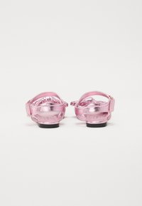 Metalliska rosa sandaler med bakrem, justerbart spänne och texturerad fotbädd. Slät yta med en låg svart sula.