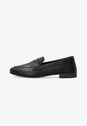 Sort læder slip-on loafer med lav hæl og stropdetalje tværs over overdelen, vist fra siden på hvid baggrund.