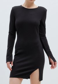 Schwarzes Langarmkleid aus glattem Stoff mit Rundhalsausschnitt, versehen mit einem Seitenschlitz und figurbetontem Schnitt, der die Körperform betont.