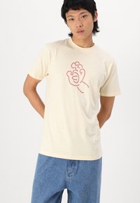 Crèmekleurig katoenen T-shirt met korte mouwen, met een rode lijn graphic van een hand op de voorkant. Rechte snit en casual pasvorm.